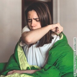 Mädchen mit Bronchitis hustet in Armbeuge