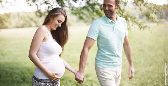 Schwangere spaziert mit Partner in der Natur: GeloMyrtol® forte unterstützt in der Schwangerschaft als pflanzliches Arzneimittel gegen Bronchitis und Sinusitis. 