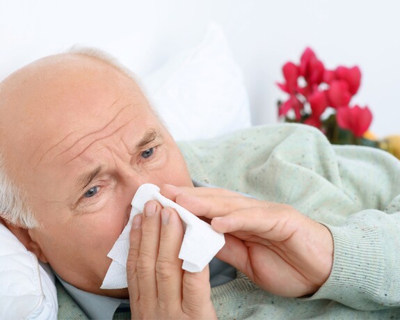 Senior mit Sinusitis putzt sich die laufende Nase.